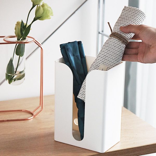 Organizer met opgerolde doeken en een bloem in vaas op houten tafel. Minimalistisch design voor moderne interieurs.