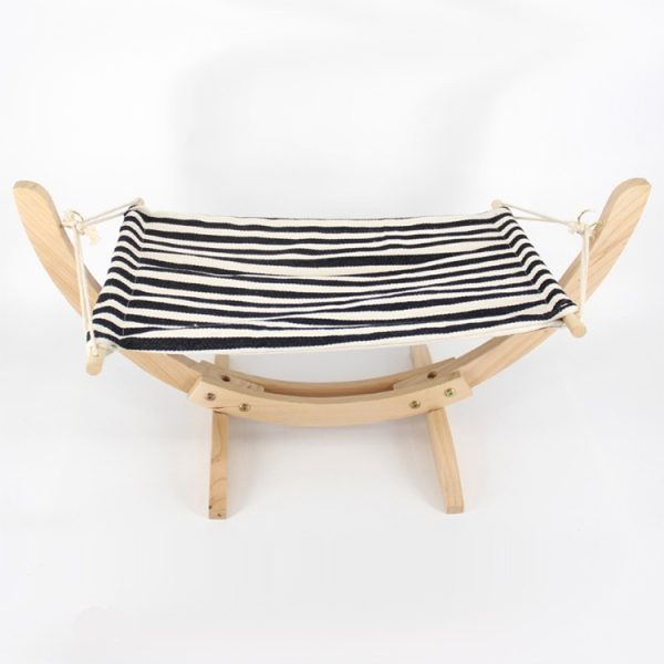 Houten poppenbed met zwart-wit gestreept stoffen matras, perfect voor kinderfantasie en rollenspel.