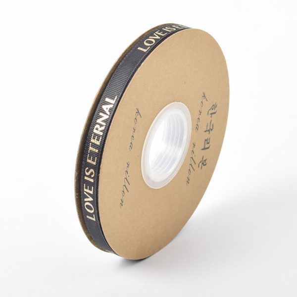 Rol zwart lint met tekst LOVE IS ETERNAL op kartonnen spoel, ideale decoratie voor cadeauverpakking.