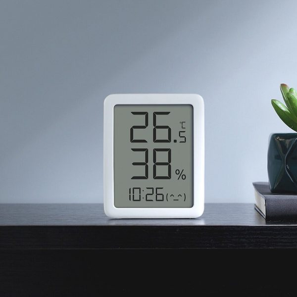 Digitale thermometer en hygrometer op een donker houten plank met temperatuur, luchtvochtigheid en tijdsweergave.
