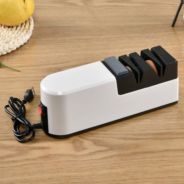 Elektrische messenslijper met meerdere slijpstations, geplaatst op een houten tafel.