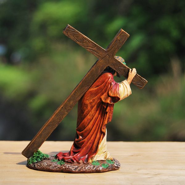 Beeld van figuur dat een houten kruis draagt op een houten oppervlak met groen wazige achtergrond.