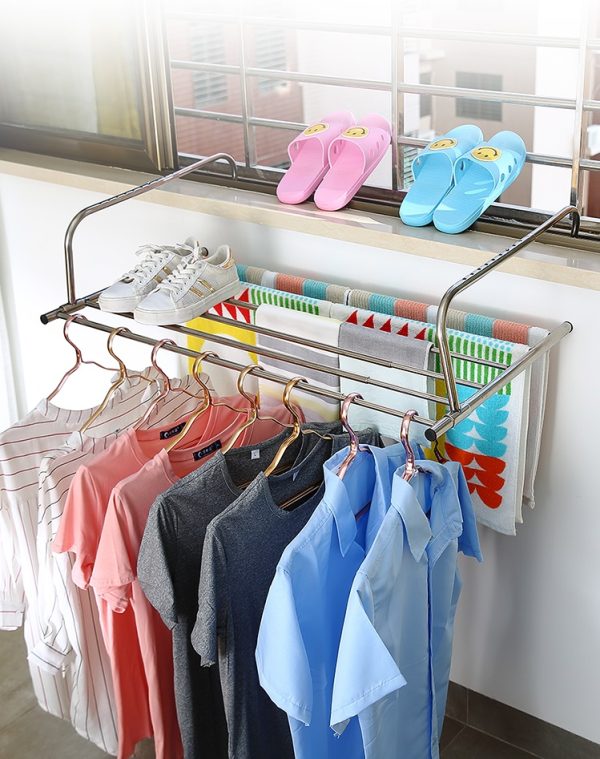 Kleding en schoenen drogen op een balkonrek met handdoeken en slippers naast een raam voor frisse lucht.