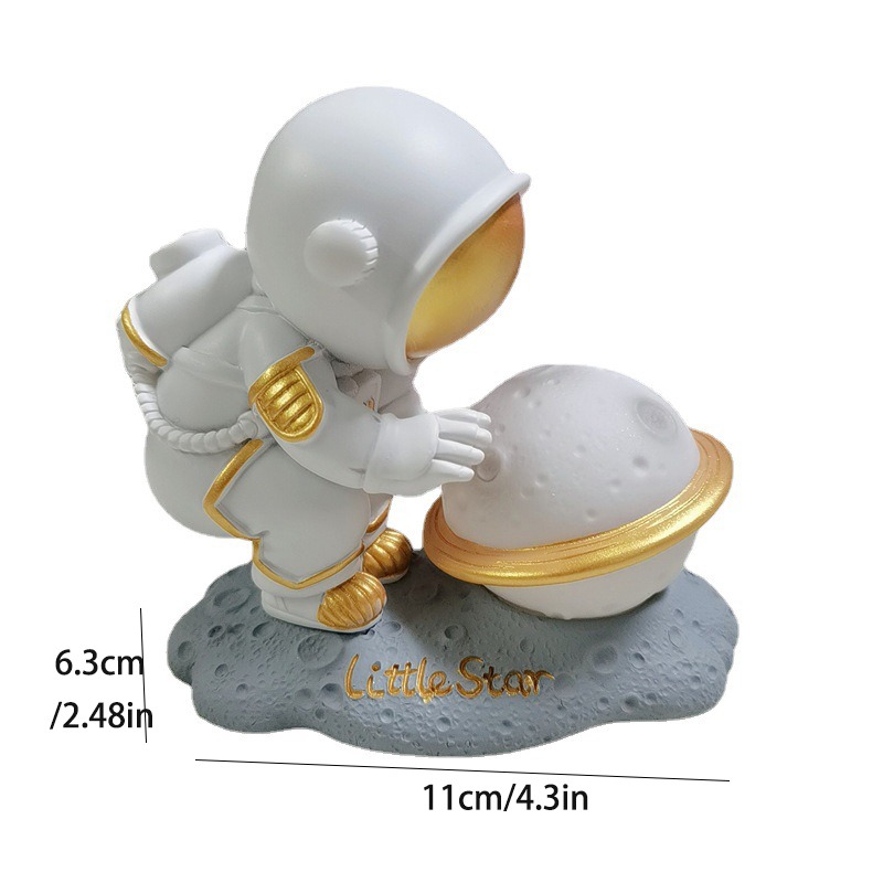 Astronautfiguurtje met gouden accenten op maansteen met planeet. Decoratief voor ruimte-enthousiastelingen.