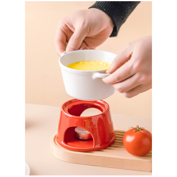 Handen plaatsen witte fonduepot op rood basis met tomaat.