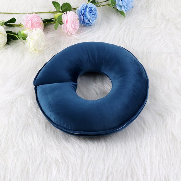 Blauw donutvormig kussen op witte pluche ondergrond met kleurrijke bloemen op de achtergrond. Comfort en decoratie.