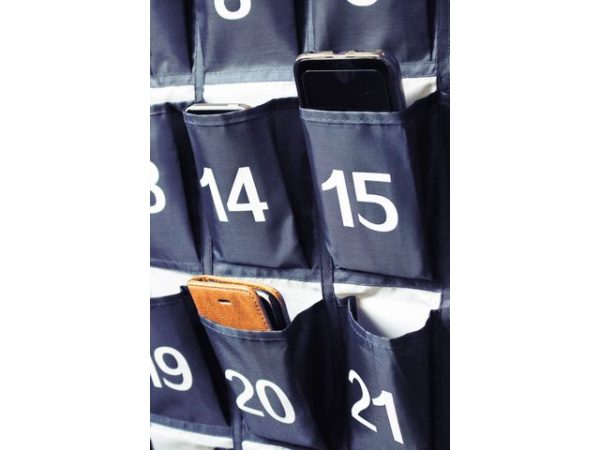 Mobiel telefoons in genummerde opbergrekken aan de muur, ideaal voor georganiseerde opslag op scholen of kantoren.