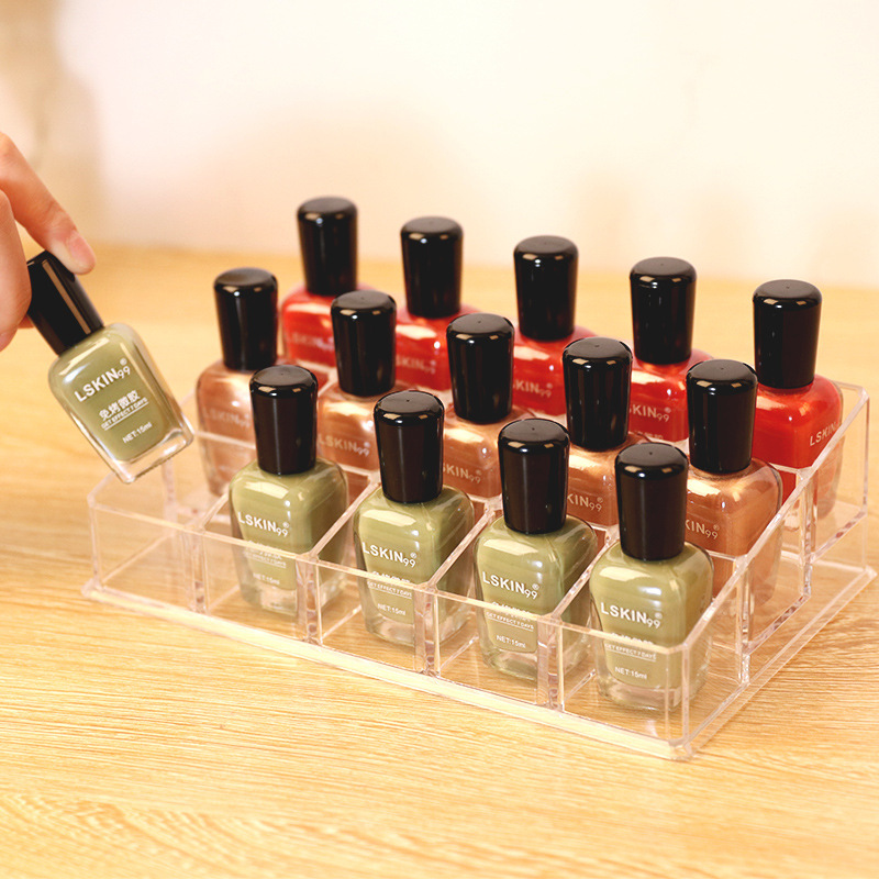 Nagellakcollectie in groene en rode tinten in doorzichtige display op houten tafel.