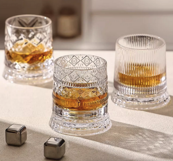 Kristallen whiskeyglazen met whisky en ijsblokjes op tafel. Luxueuze drankervaring in elegant glaswerk.
