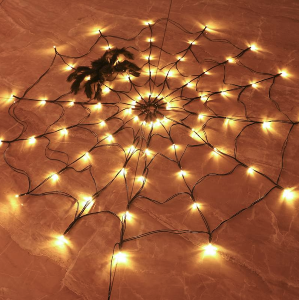 Lichtgevend spinnenweb met oranje lampjes op een warme ondergrond voor Halloween-decoratie.