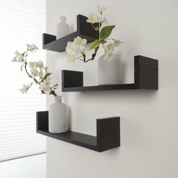 Zwevende zwarte planken met bloemen en witte vazen tegen een witte muur voor moderne woondecoratie.