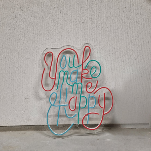 Neon tekst in rood en blauw tegen een grijze muur: You make me happy.