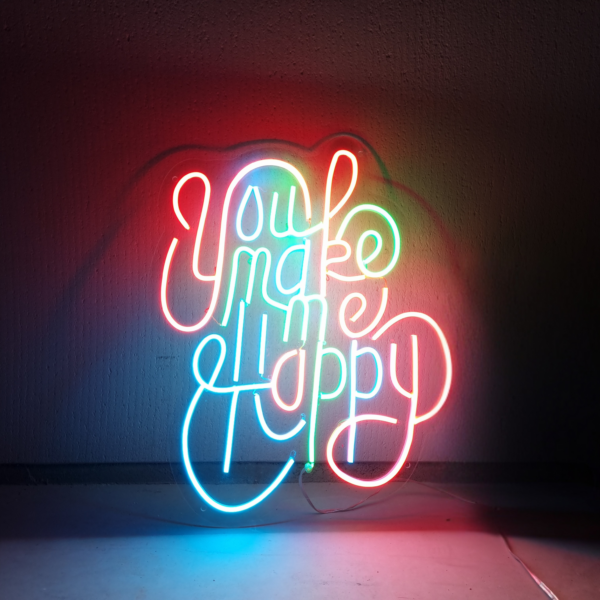 Neonbord met de tekst You make me happy in kleurrijke lichten tegen een donkere achtergrond.