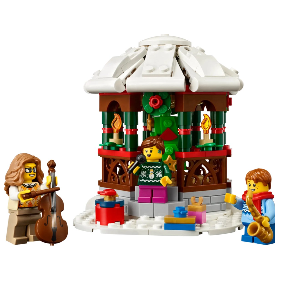 LEGO kerstmarkt met drie minifiguren die muziek spelen naast een sneeuw bedekt podium en feestelijke decoraties.